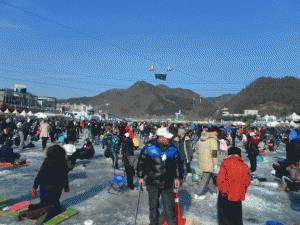 A crowd of people trying their luck at ice fishing at the Hwacheon Sancheoneo Ice Festival.