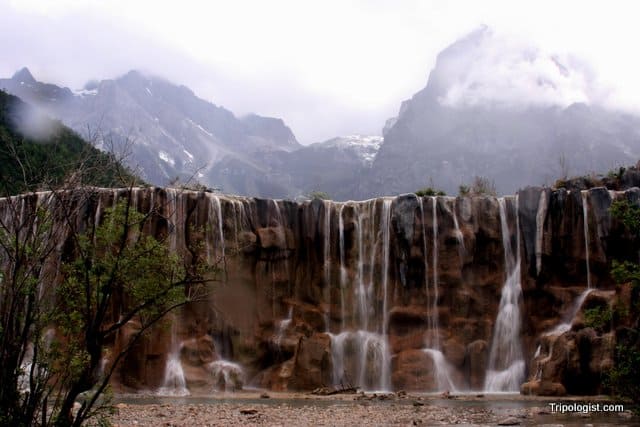 A waterfall on the White River with Jade Dragon Snow Mountain in the background.