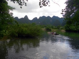 My wife and our 2 bikes being paddled across the Yulong River on a homemade bamboo raft.