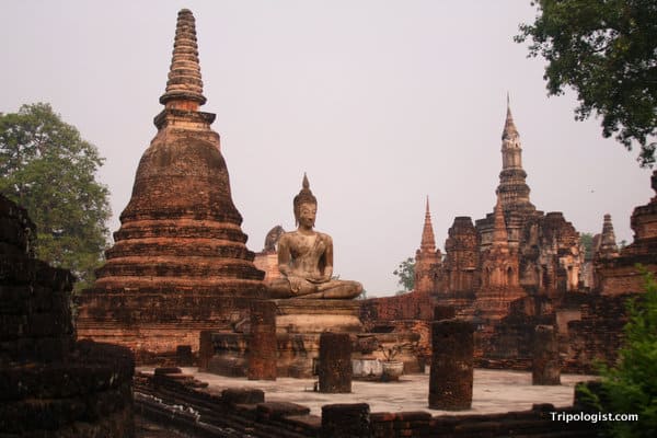 A seated Buddha perched amid a myriad of chedis at Wat Maha That in the Sukhothai Historical Park.